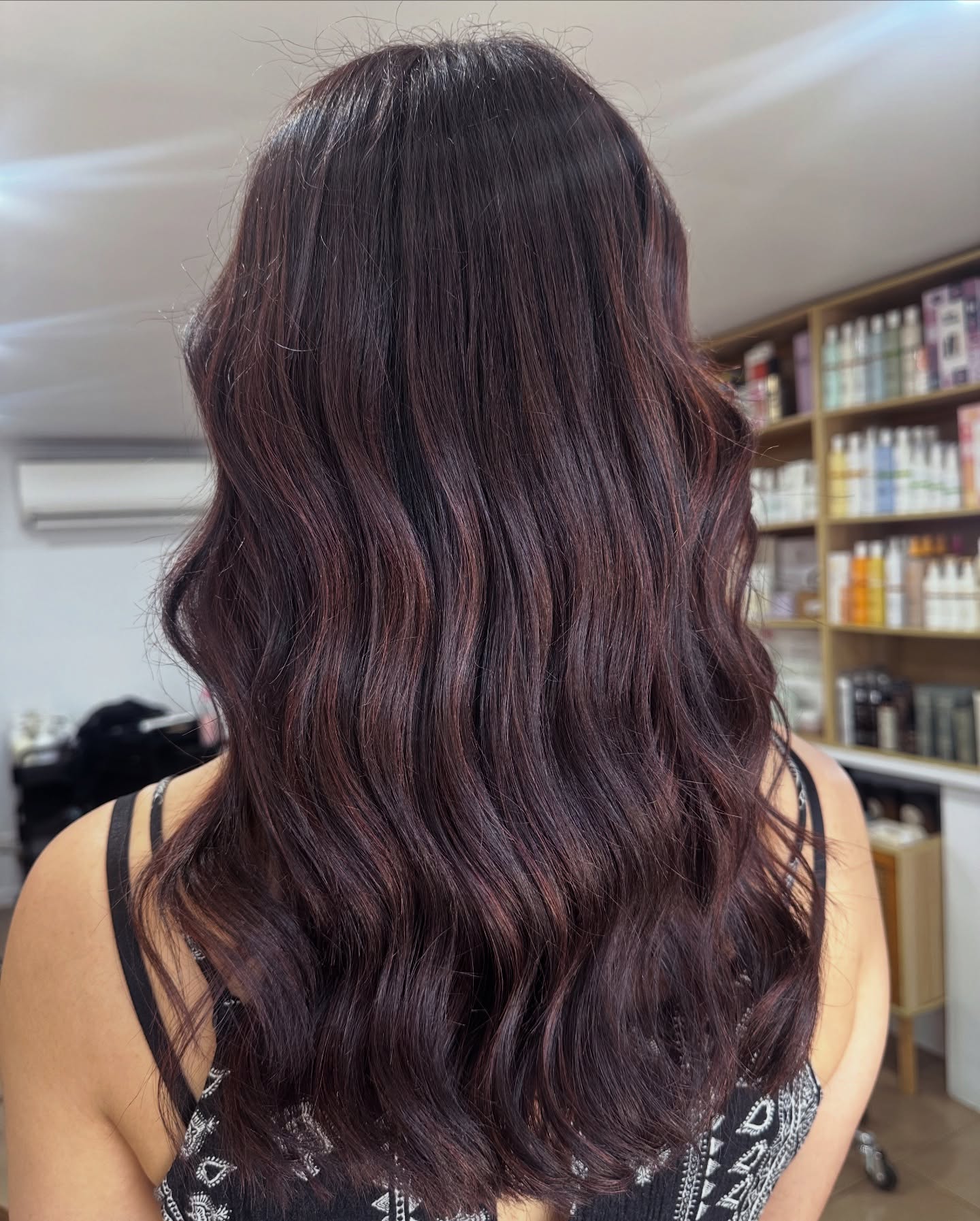 Rich brunette hair colour with subtle warm highlights and waves