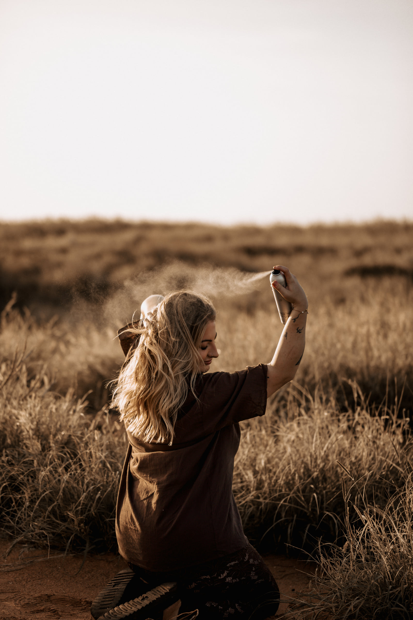 Kate Bonnie applying professional hair treatment product spray in Pilbara grassland South Hedland